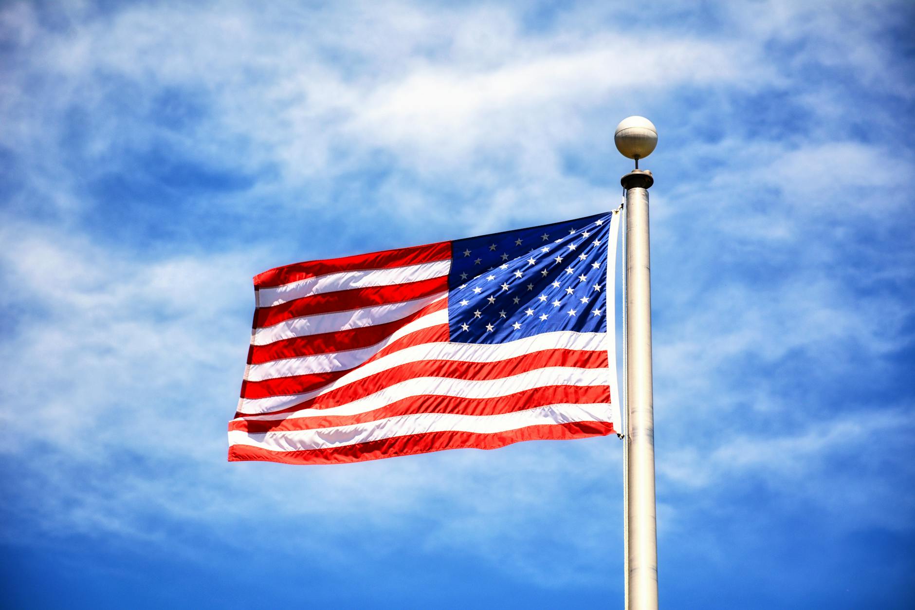 Vibrant American flag flying against a clear blue sky, symbolizing freedom and patriotism.